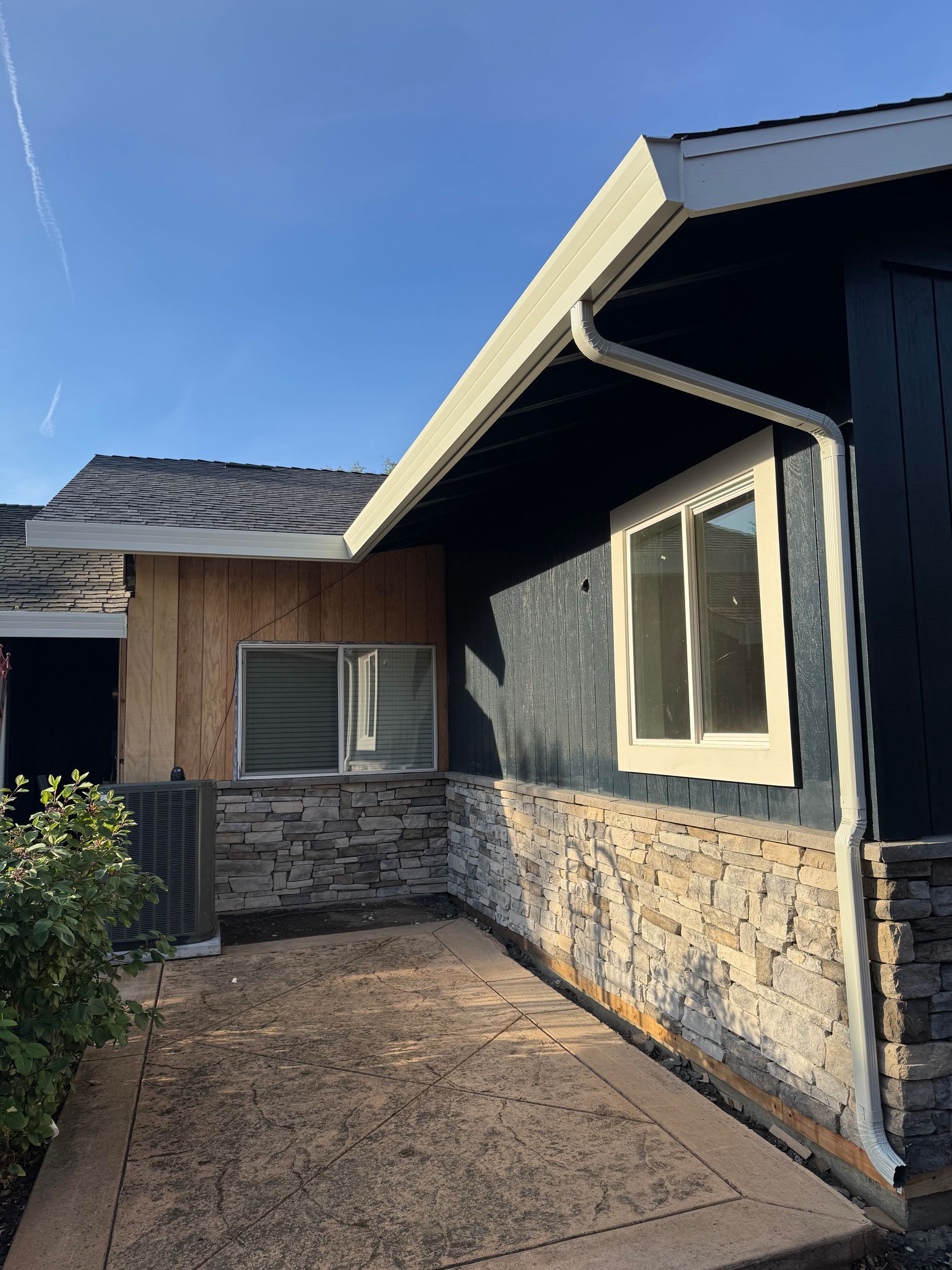 A house with a stone wall and a gutter on the side of it.