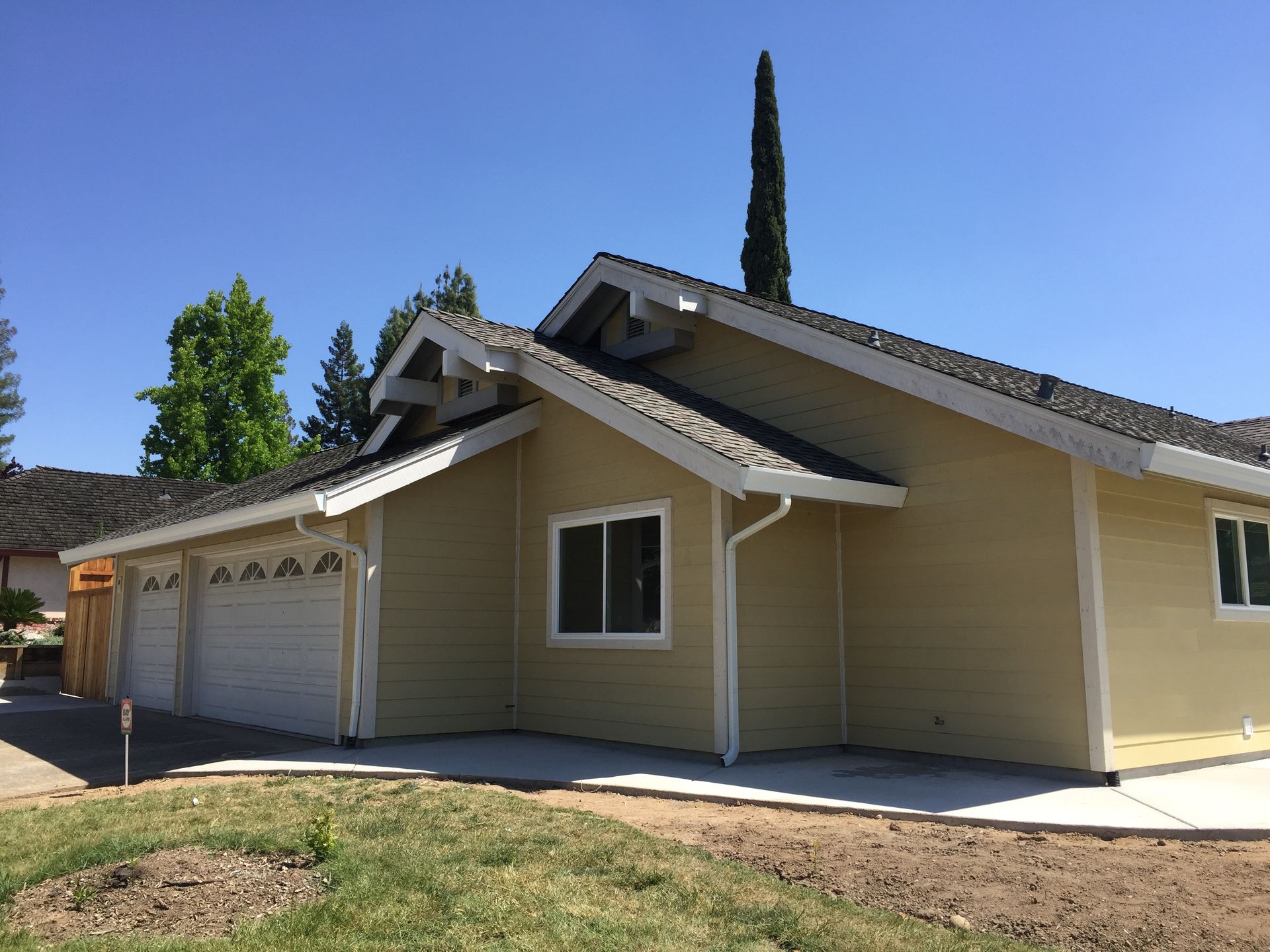 A beige house with a white garage door and a blue sky in the background.