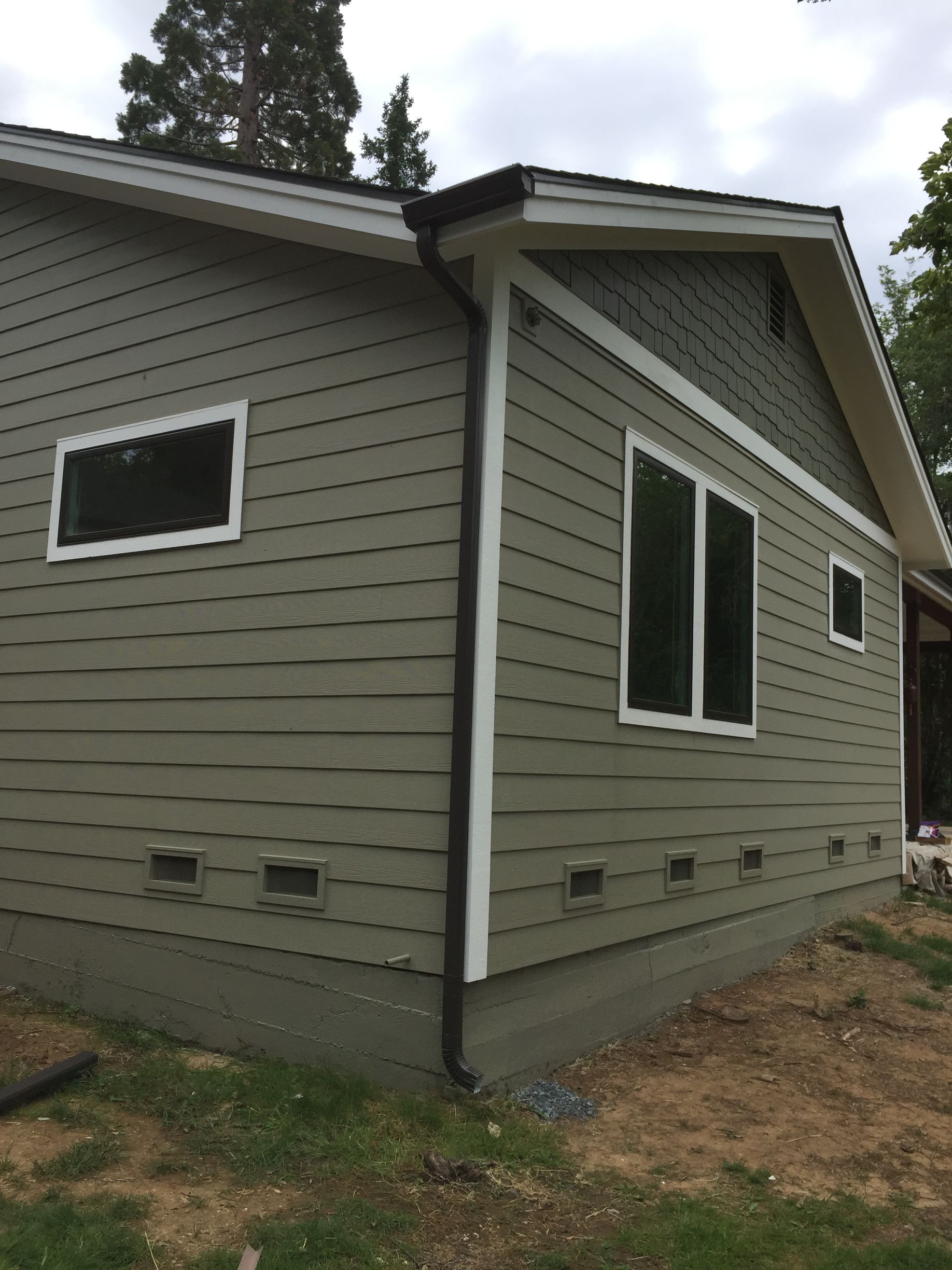 A house with a lot of windows on the side of it and a gutter after it got repaired
