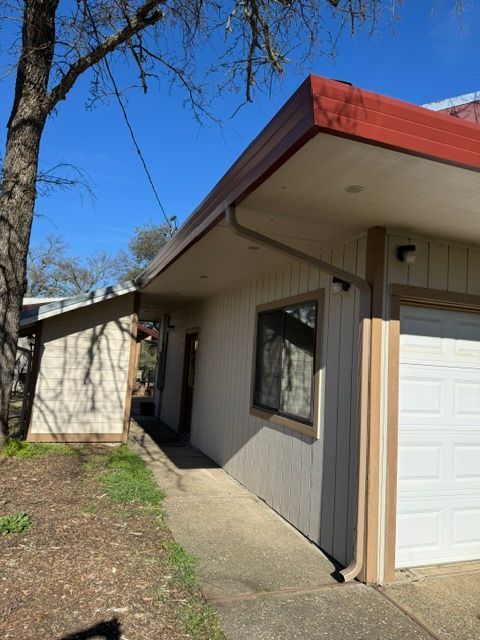 A white house with a red roof and a white garage door