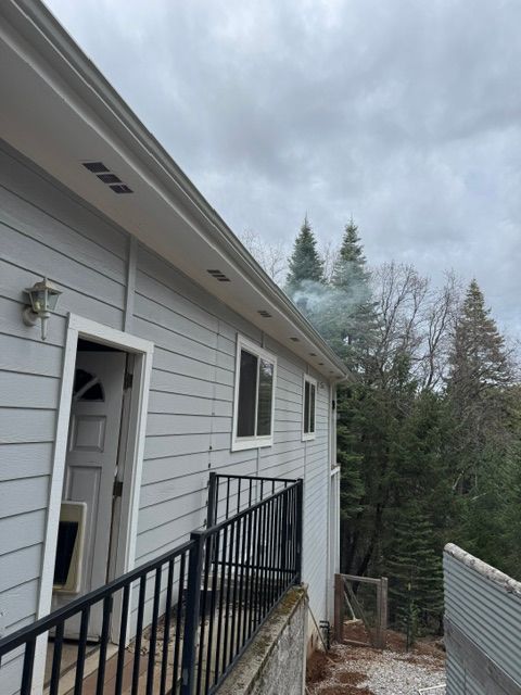A white house with a black railing and trees in the background