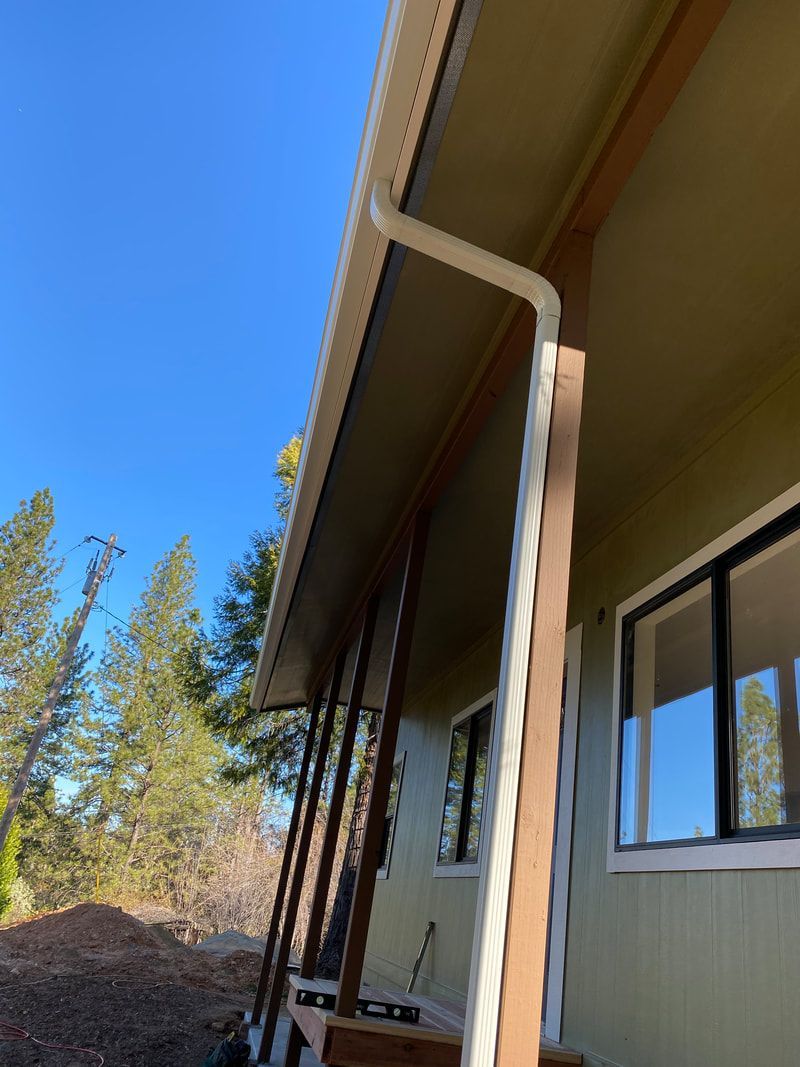 A house with a porch and a gutter on the side of it.