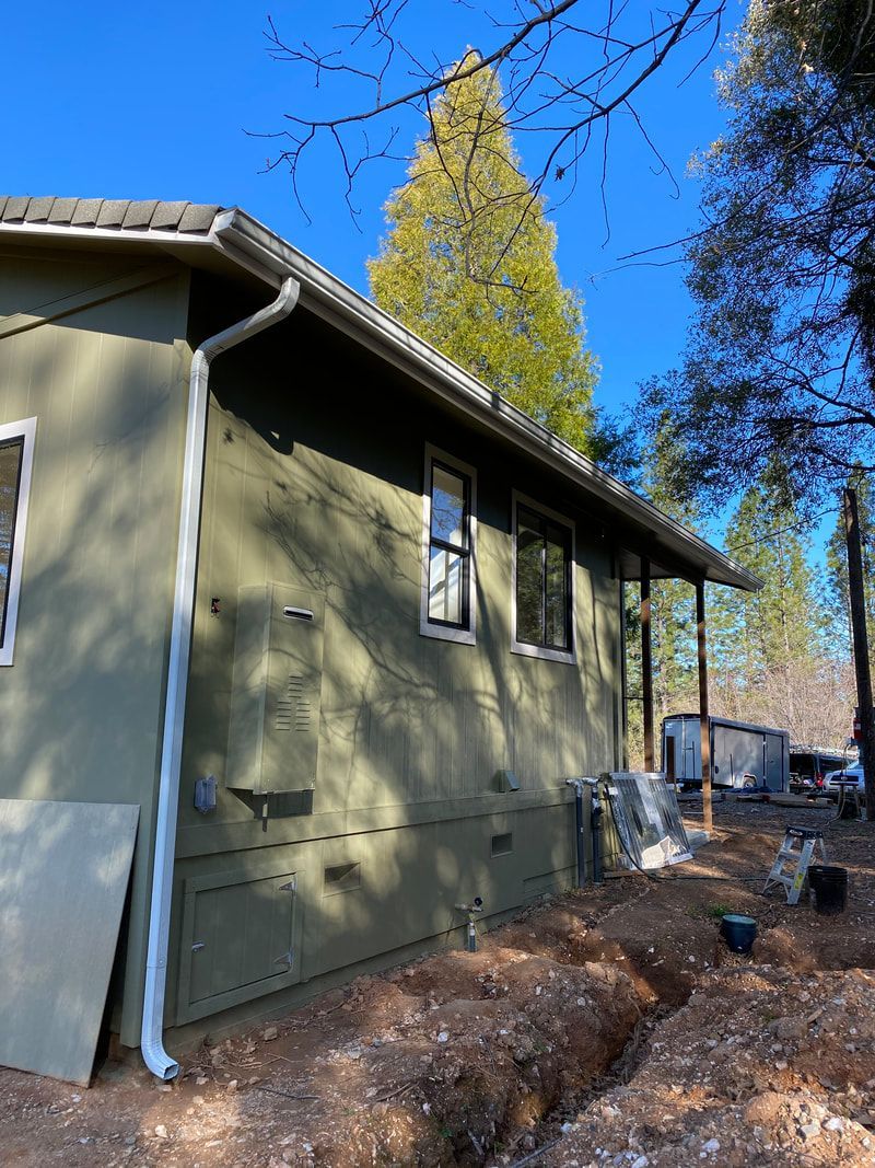 A green house with a gutter on the side of it
