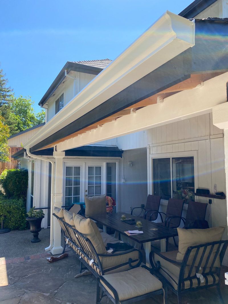 A patio with a table and chairs under a roof.