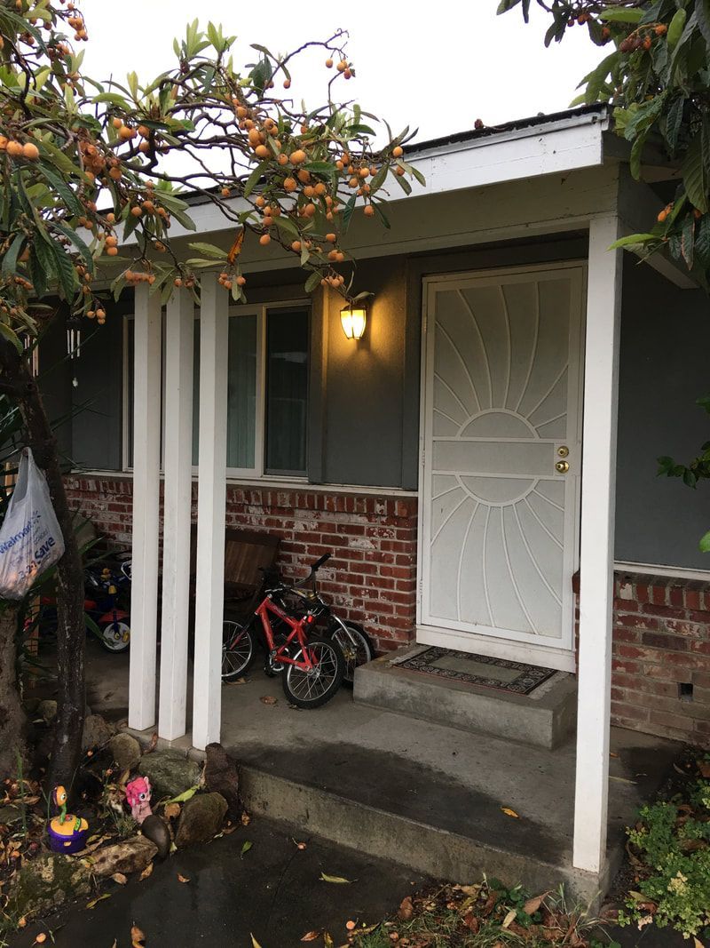 A house with a porch and a bicycle parked in front of it.