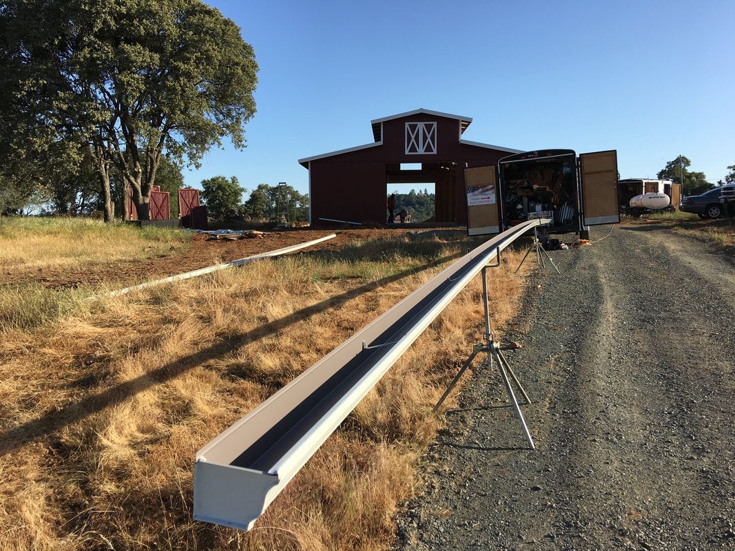 A large barn is being built in the middle of a dirt road.