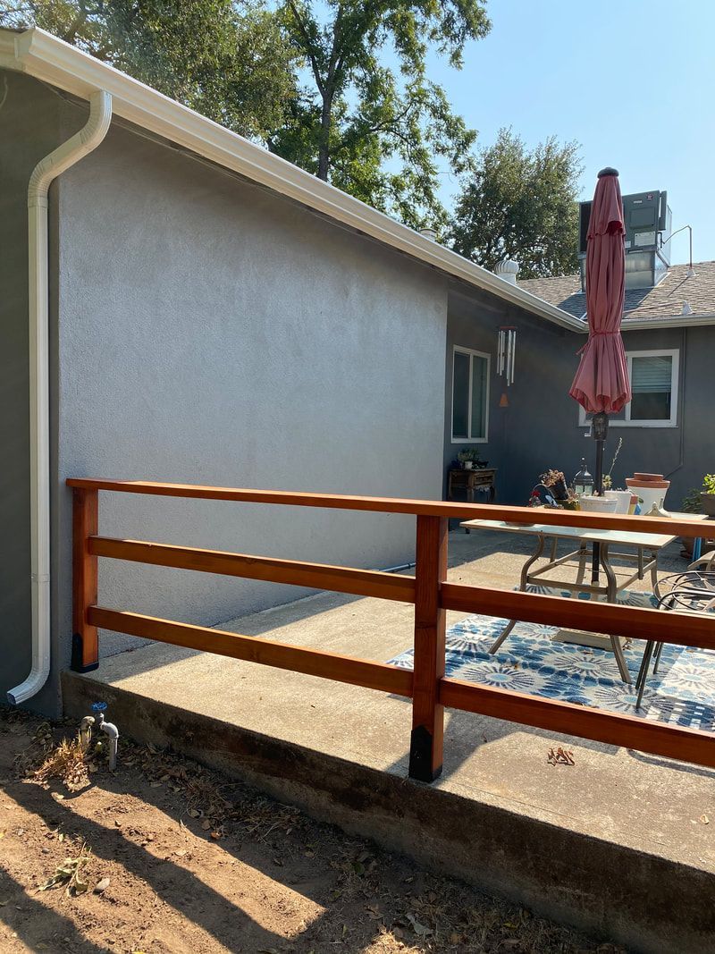 A wooden fence surrounds a patio area in front of a house.