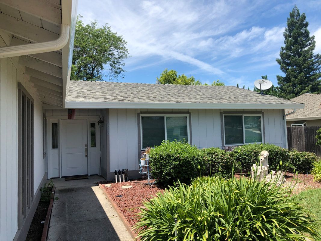 A white house with a gray roof and a driveway in front of it.