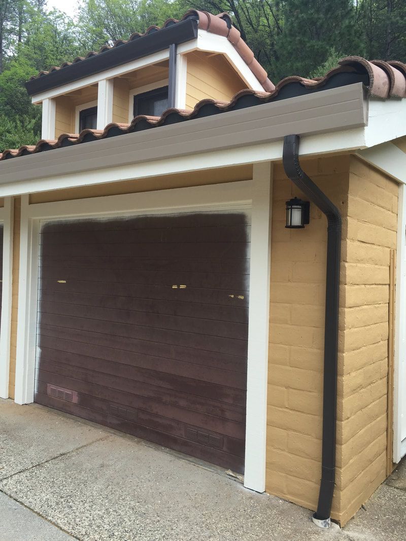 A yellow house with a brown garage door and a gutter