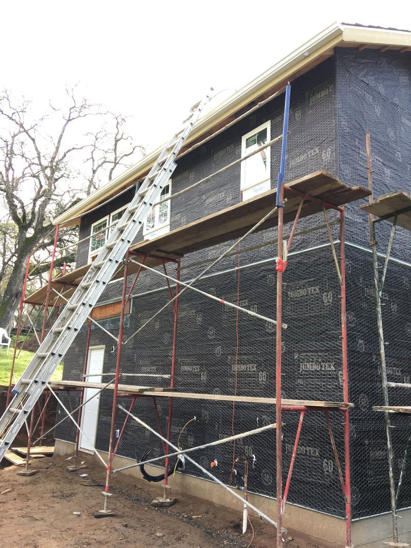 A house is being built with scaffolding and a ladder.