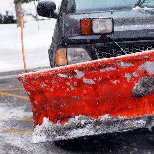a snow plow is being used to remove snow from a parking lot .