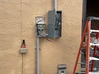 A ladder is sitting next to a box on the side of a building.