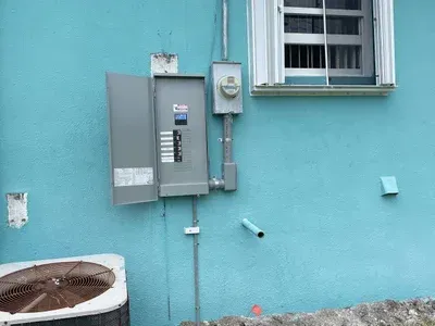 There is a box on the side of a building next to a window.