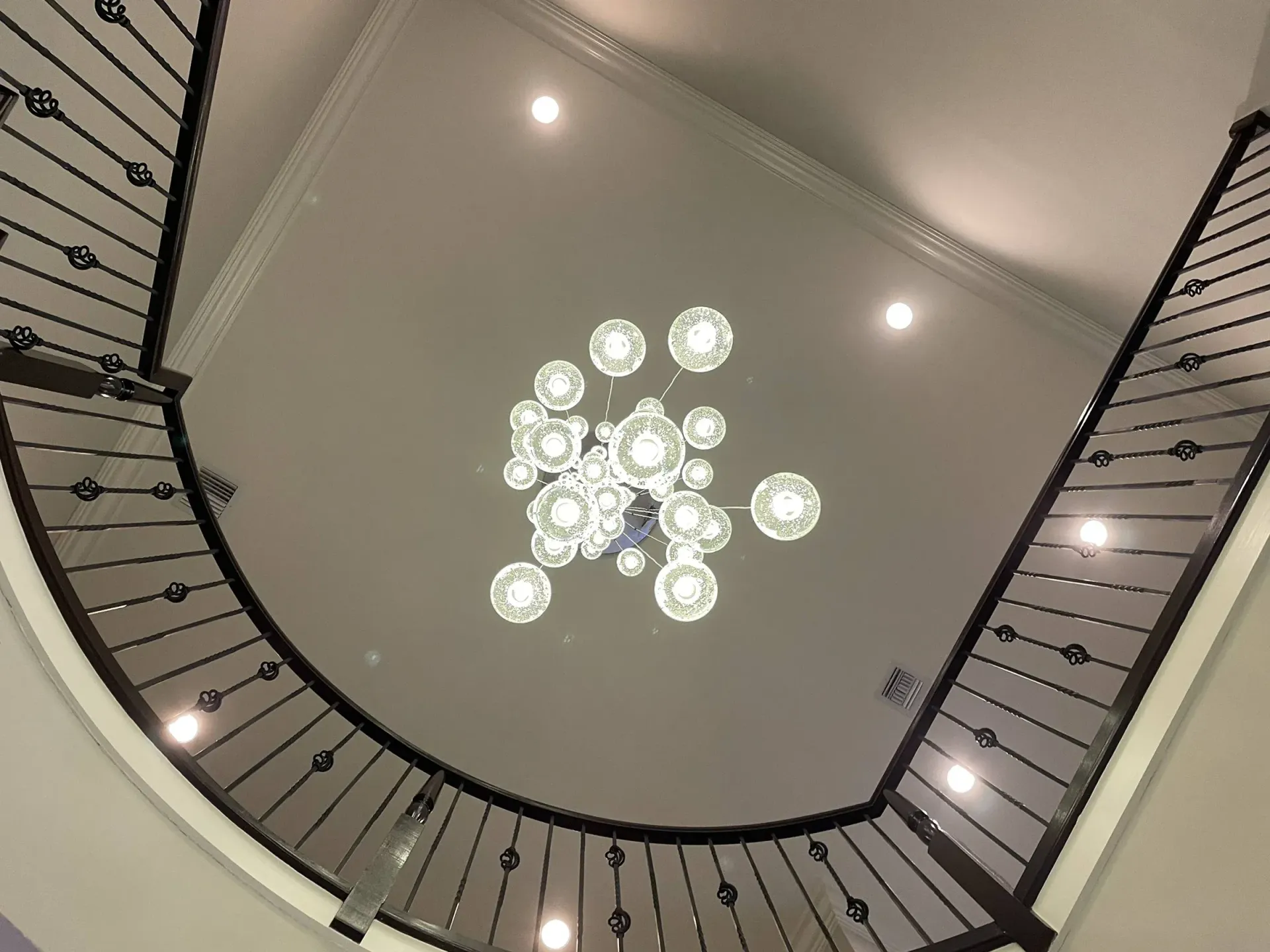 Looking up at a spiral staircase with a chandelier hanging from the ceiling