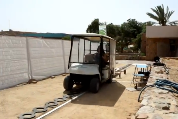 A man is driving a golf cart on a wireless charging track to test the charging status