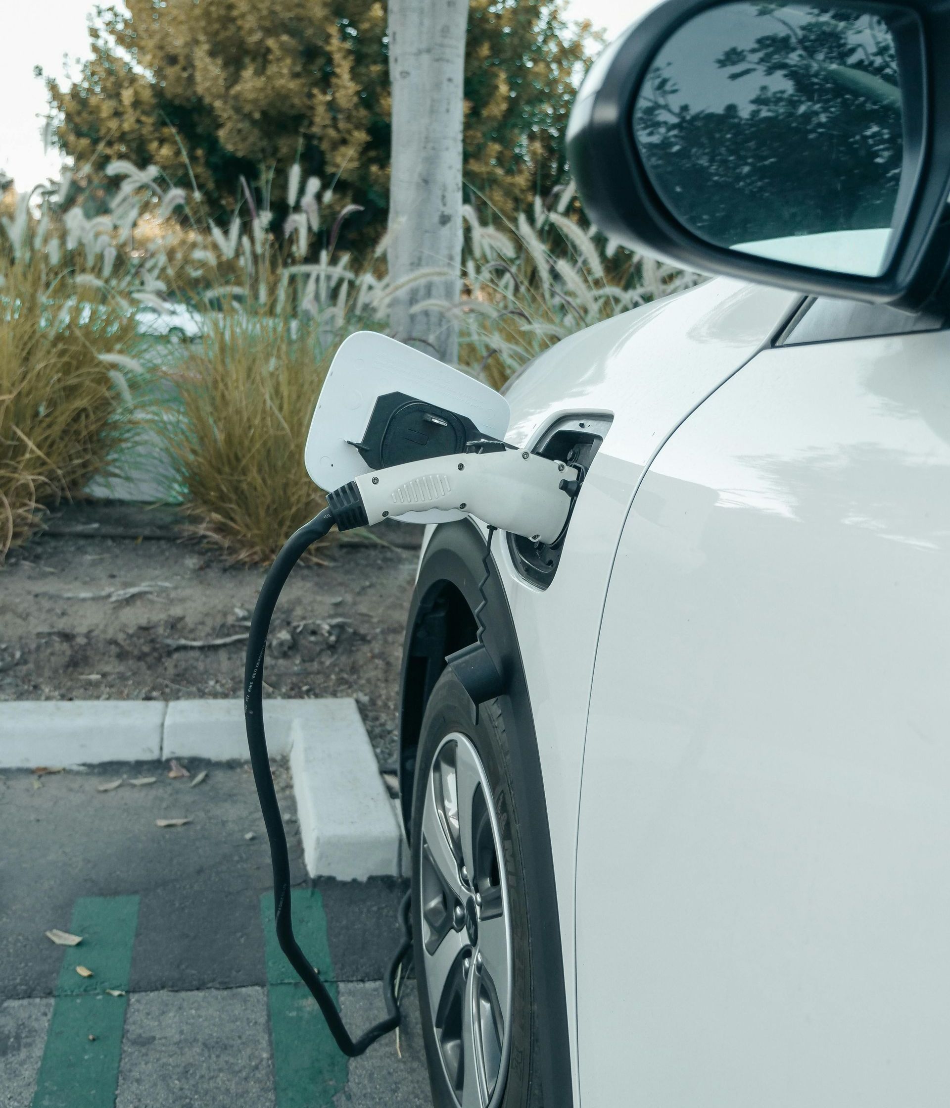 A white electric car is being charged in a parking lot