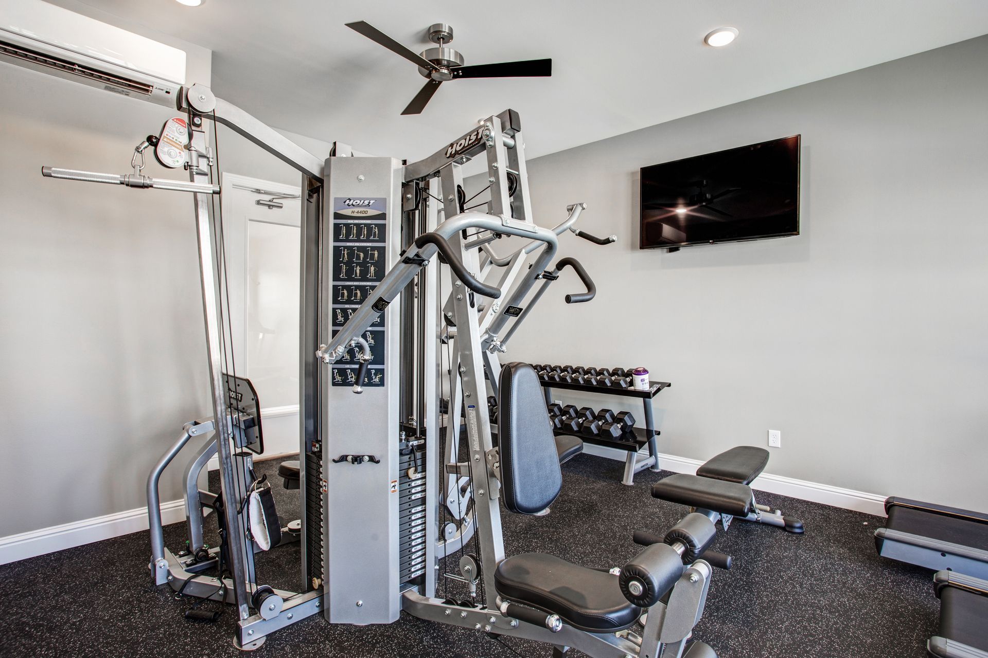 A gym with a ceiling fan and a television on the wall.