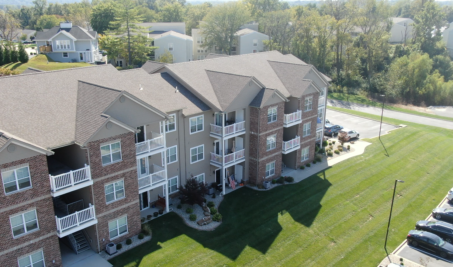 An aerial view of a large apartment building with cars parked in front of it