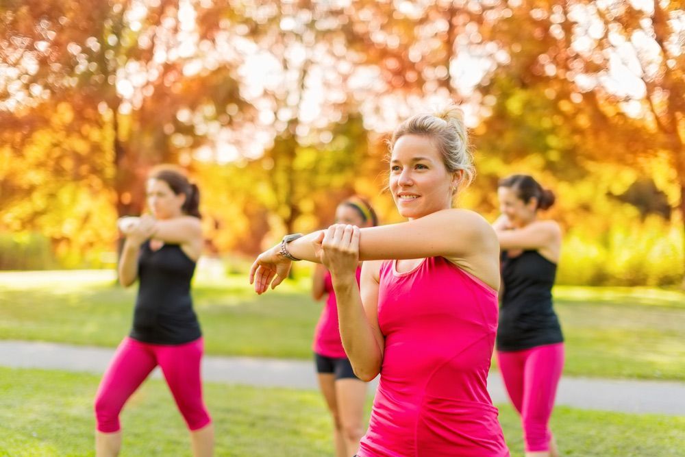 A Group Of Women Are Doing Stretching Exercises In A Park — Pink Up Gold Coast in Southport, QLD