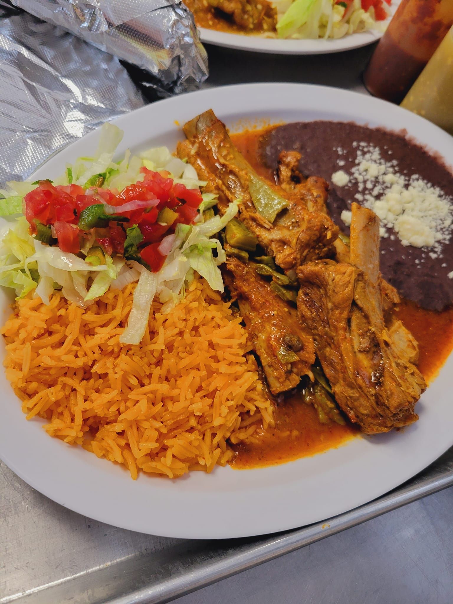 A white plate topped with rice , beans , meat and vegetables.