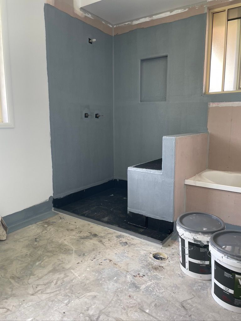 There are two buckets of paint in the bathroom.