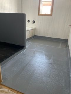 A bathroom with a gray floor and a window.