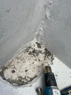 A close up of a corner of a wall with a drill.