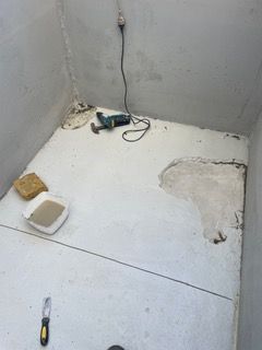 A room with a drill and a spatula on the floor.