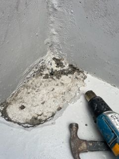 A hammer and a drill are sitting on a white surface.