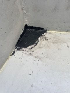 A close up of a corner of a white wall with black stains on it.