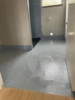 A room with a gray floor and a wooden floor.