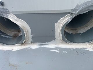 A close up of two holes in a wall that have been sealed with silicone.