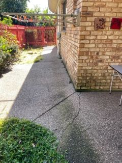 A brick building with a sidewalk and a table in front of it.