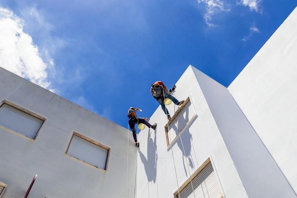 A person is painting a wall blue with a paint roller