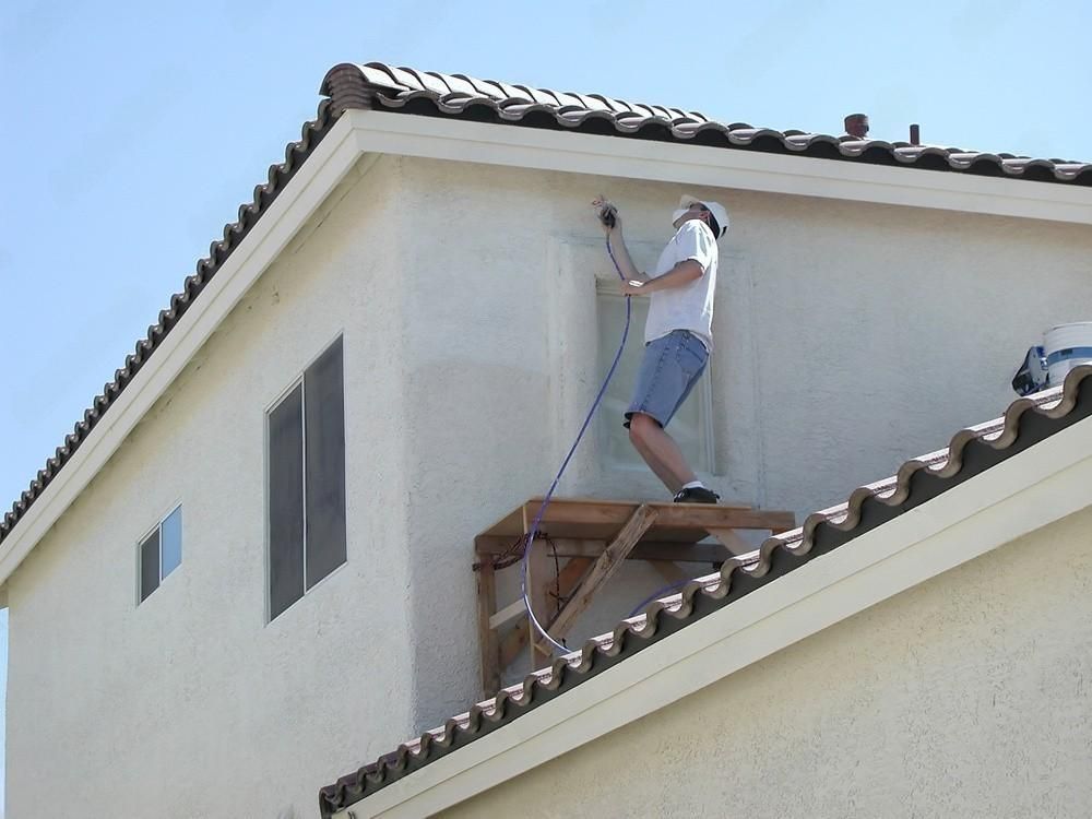 A man is painting a blue wall with a paint roller.