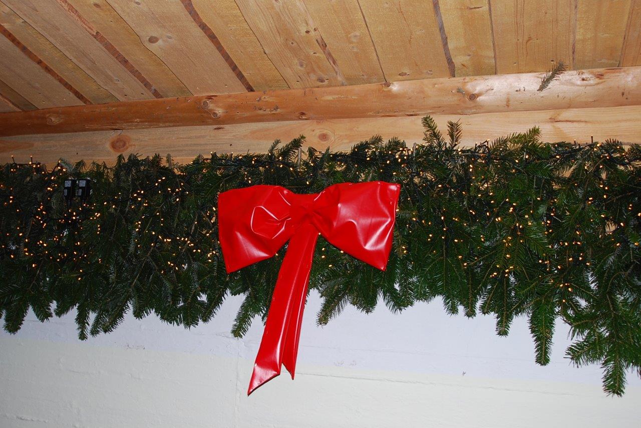 Eine rote Schleife hängt an einer Weihnachtsgirlande