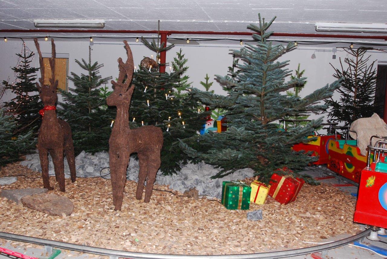 2 gebastelte Rentiere und Geschenken stehen vor Weihnachtsbäumen