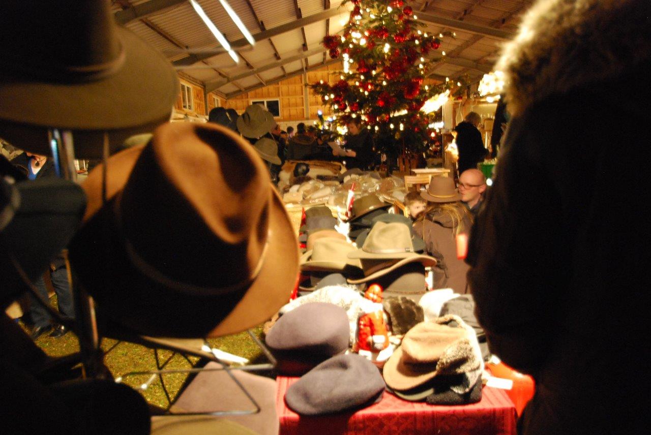 Ein Tisch voller Hüte mit einem Weihnachtsbaum im Hintergrund