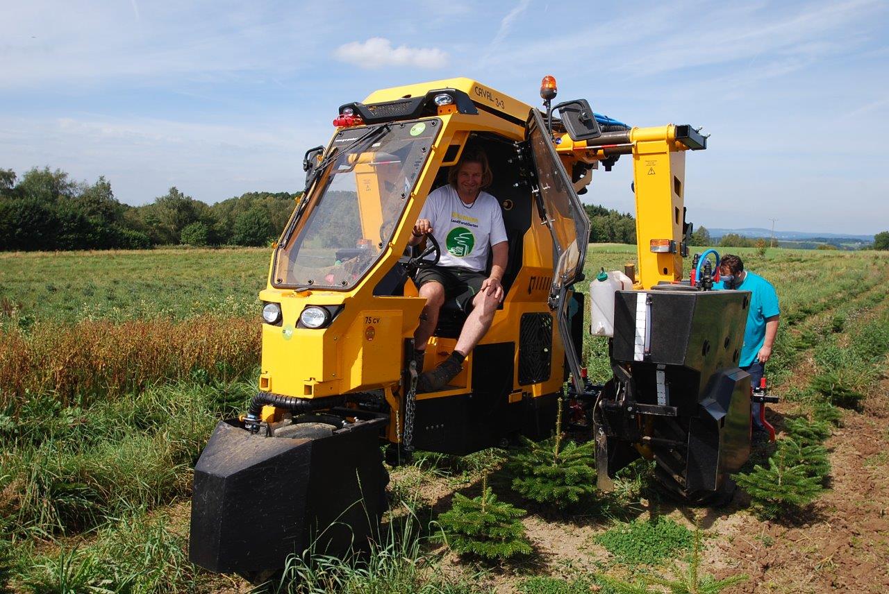 Ein Mann sitzt in einem gelben Traktor auf einem Feld.