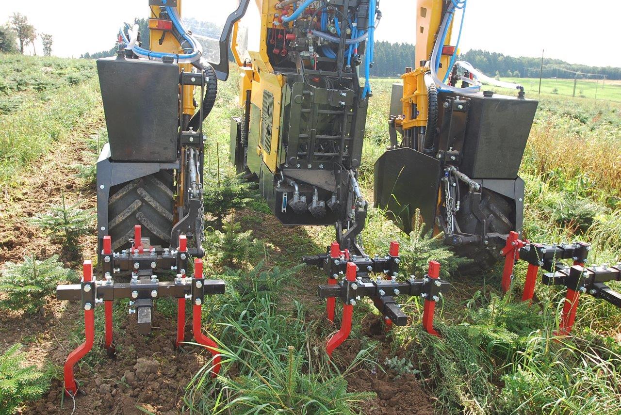 Ein gelb-schwarzer Traktor pflügt ein Grasfeld.