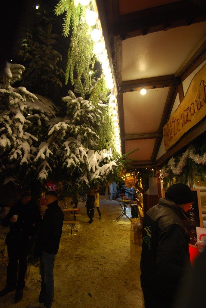 Eine Gruppe von Menschen geht nachts eine verschneite Straße entlang.