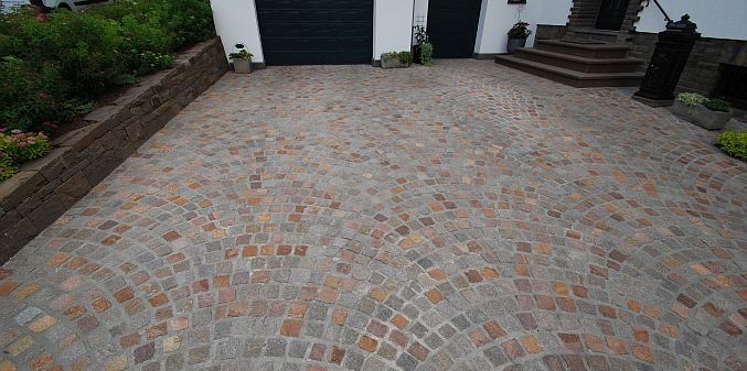 Eine gepflasterte Auffahrt vor einem Haus mit Garage.