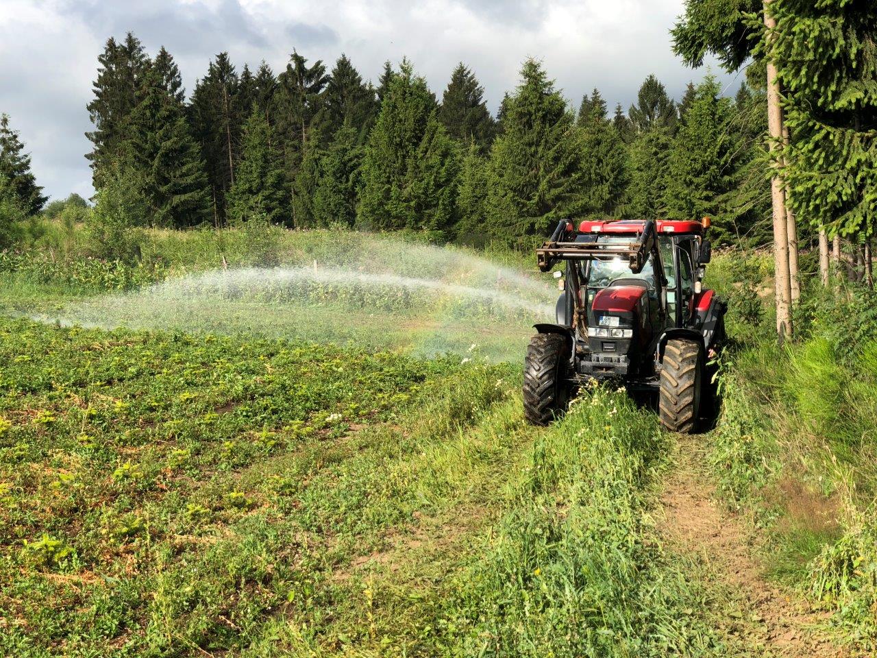 Traktor sprüht Wasser auf Wiese