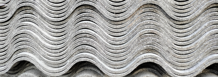 A close-up of a stack of asbestos sheets with a wave pattern.