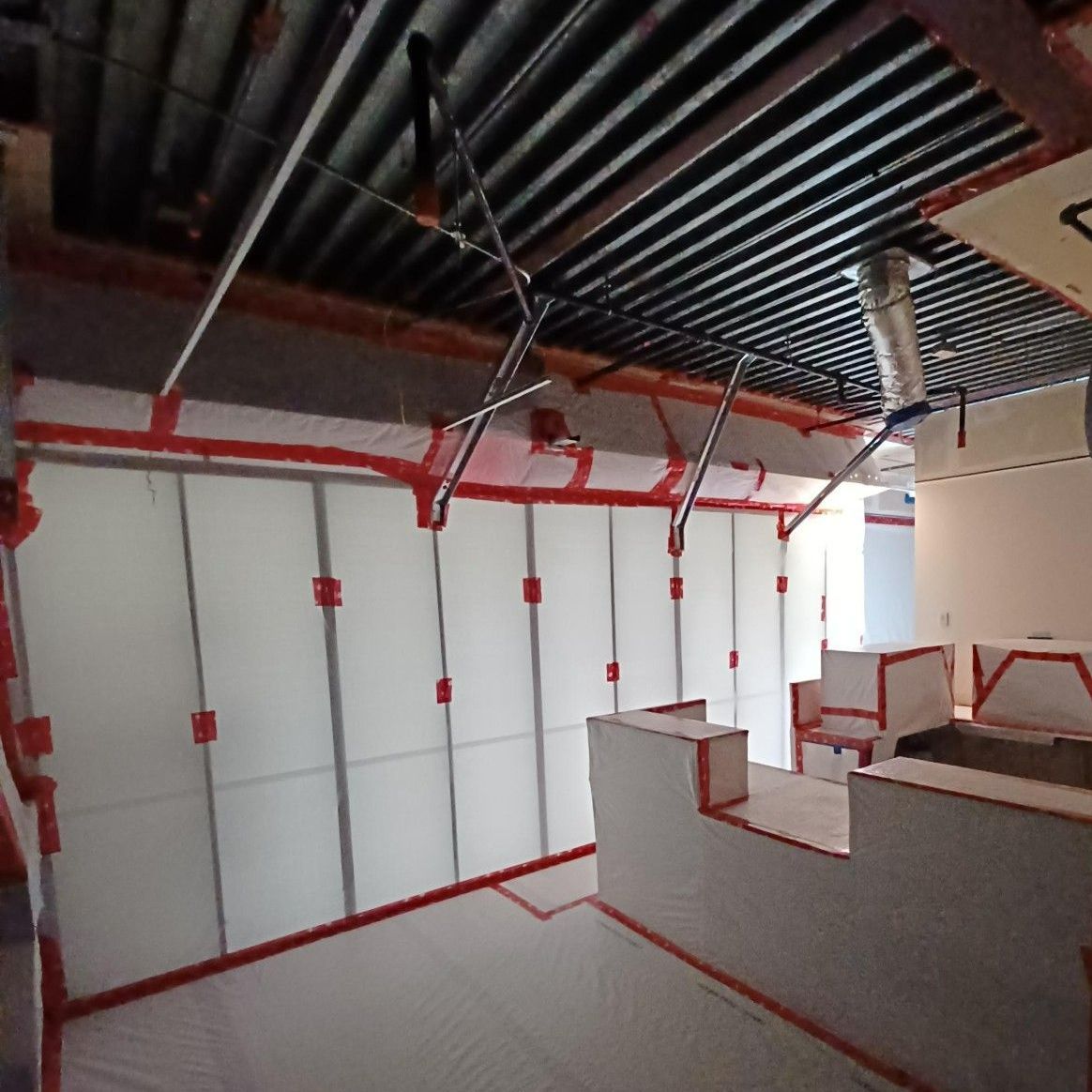 A room with a ceiling that has a lot of pipes hanging from it