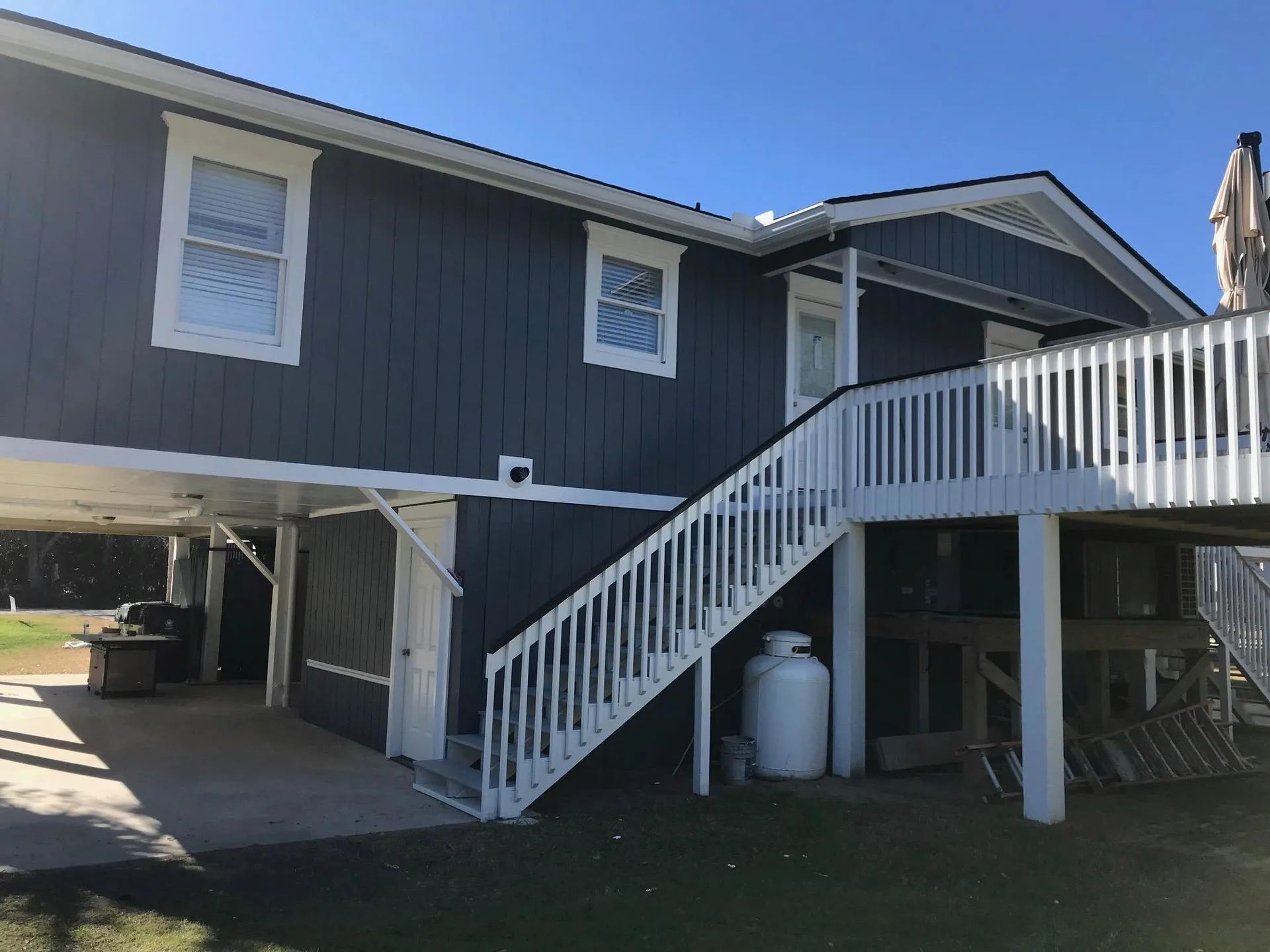 Two-story house with dark blue siding, white trim, and a staircase leading to a deck.