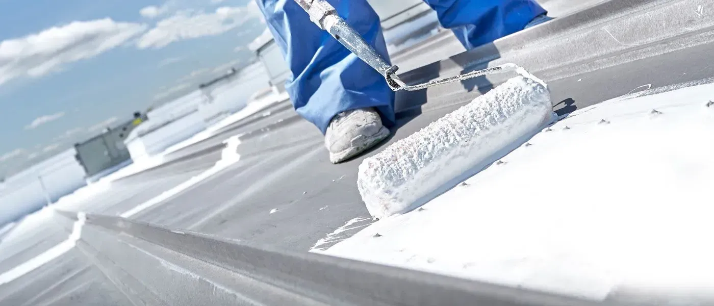 A person is painting a roof with a roller.
