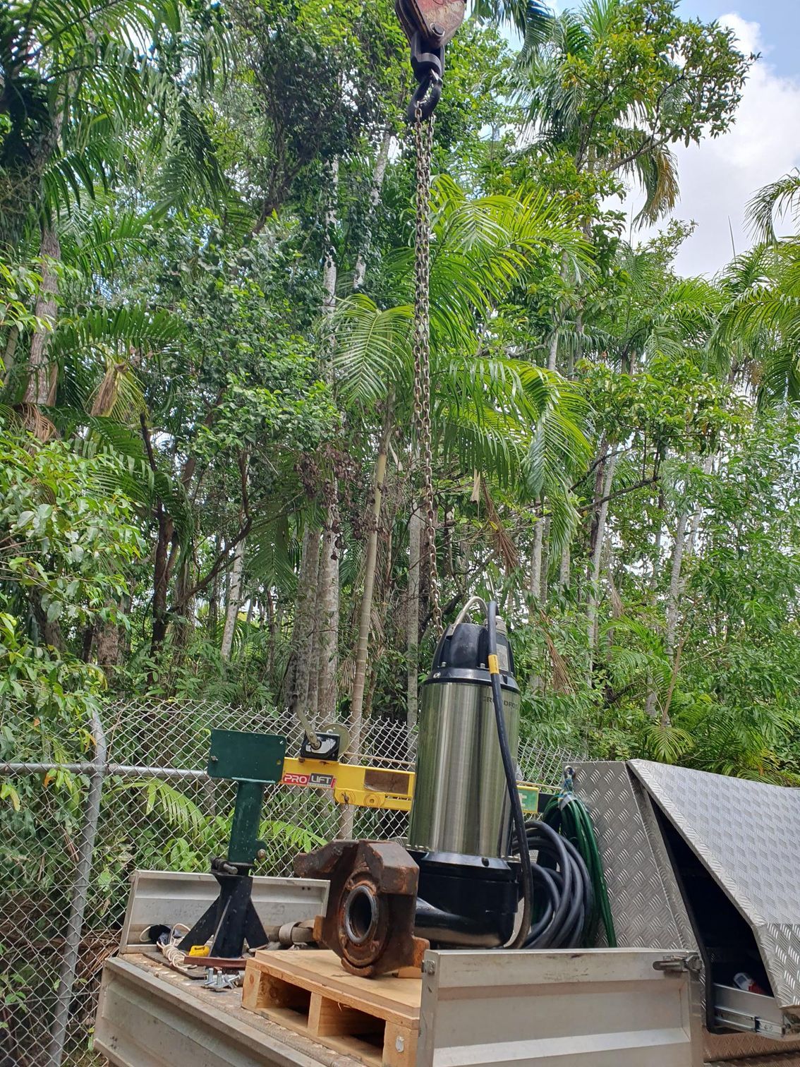 A crane is lifting a pump out of a truck.