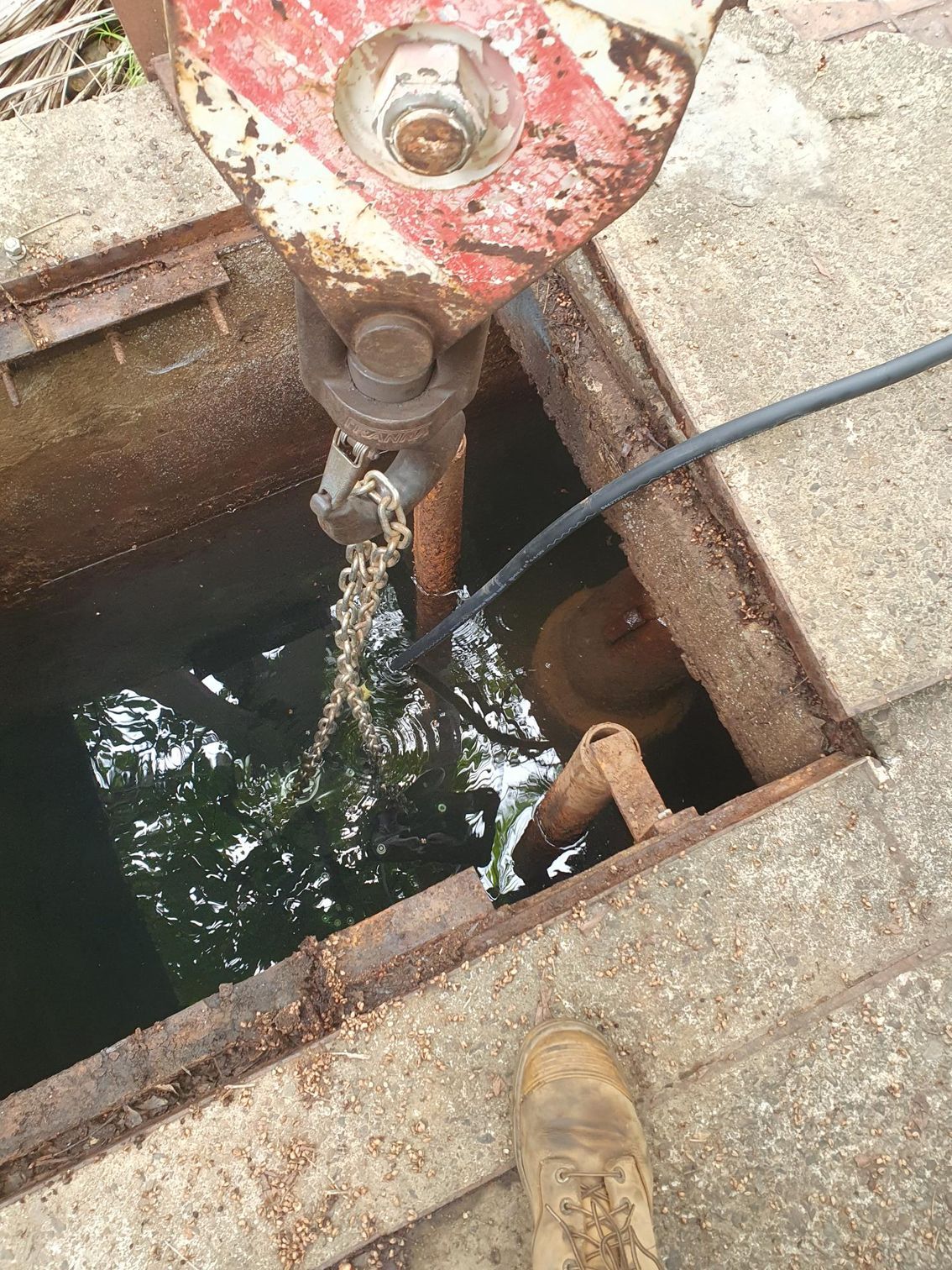 A person is standing in a hole with a hose coming out of it.