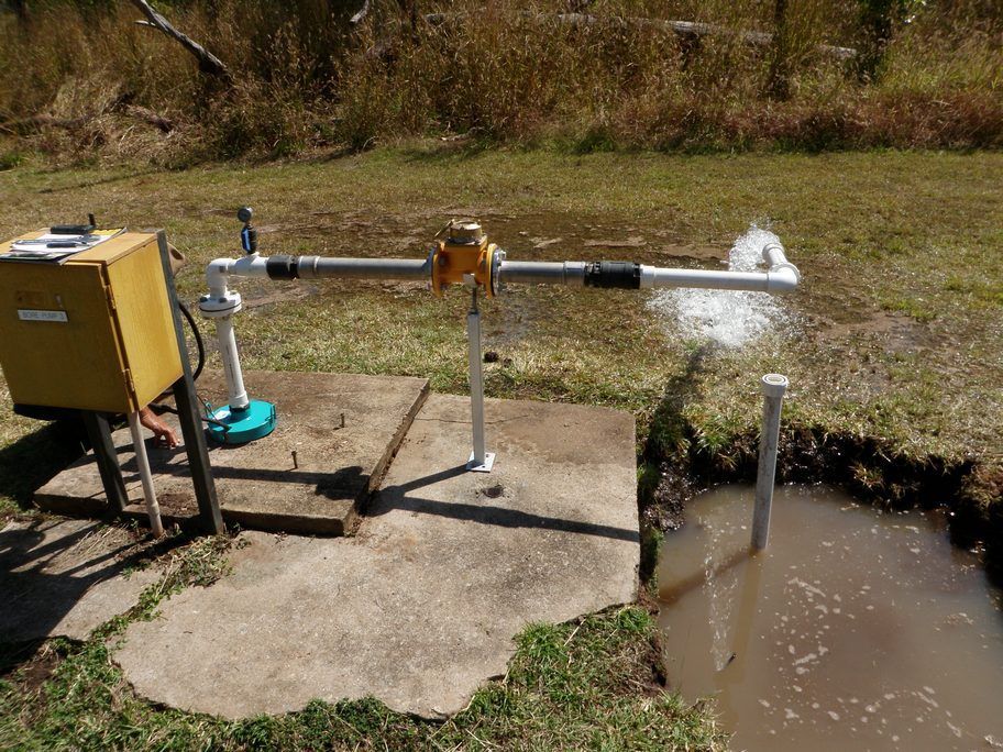 A yellow box is sitting next to a pipe in the grass.